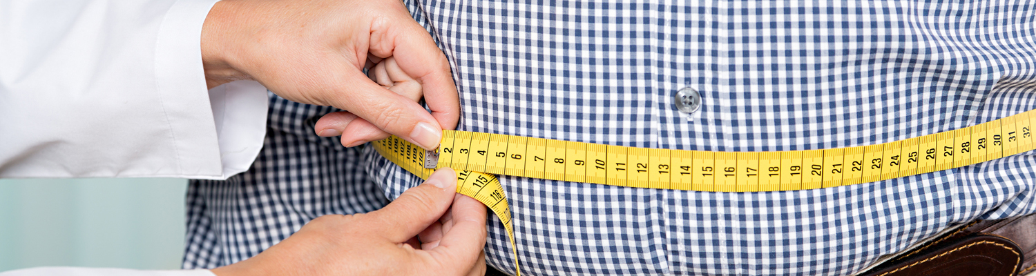 Doctors hands hold measuring tape around man's waist