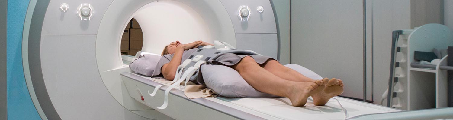 Female patient lying down entering circular CT machine