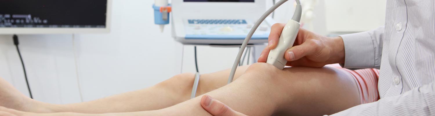 Technician moving wand over knee as performing ultra sound