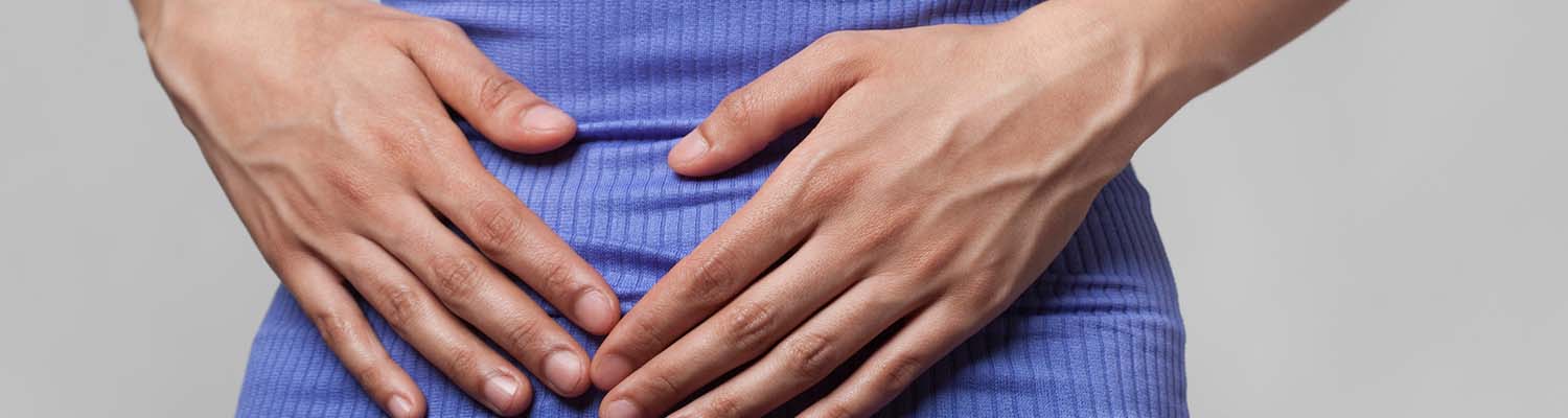 Woman in bright purple shirt holds her hands to her abdomen